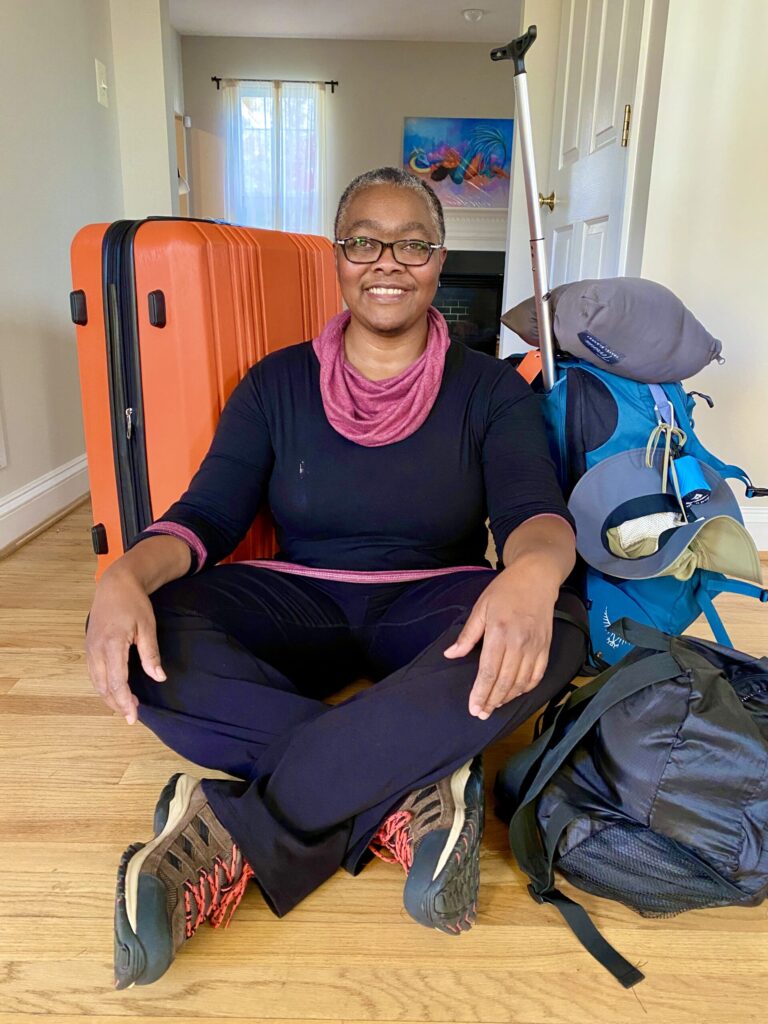 Mel sitting cross-legged on floor surrounded by luggage